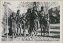 Group of women and children singing, with expedition truck in background (print is a cropped image)