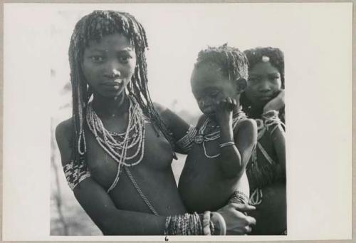 Kashibi, wife of Tango or /Tagoo, holding a baby and standing next to Shamba, daughter of /Oashay (print is a cropped image)