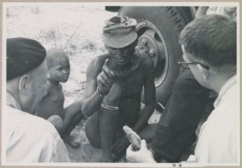 "/Gao Overalls" and a boy sitting with O.P.M. Prozesky and Nicholas England sitting across from him, seen from behind (print is a cropped image)