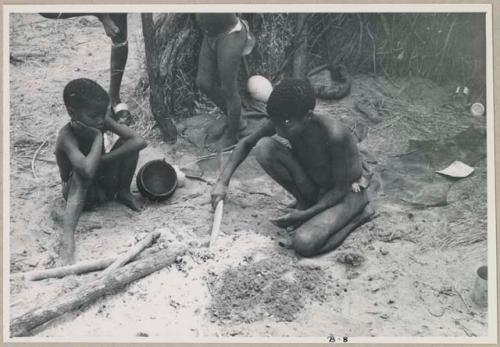 "/Gao Overalls'" son compressing the cocoon shells and steaming them in hot ashes (print is a cropped image)