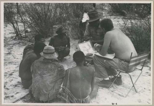 Wilhelm Camm and Nicholas England in chairs with a sound recorder interviewing five men sitting on the ground (print is a cropped image)