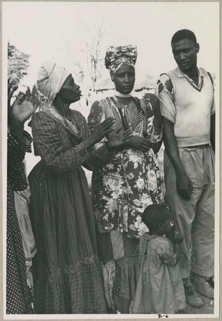 Ananias standing in a line with women who are clapping (print is a cropped image)