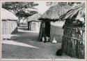 Woman lying in the doorway of a hut, seen from a distance (print is a cropped image)