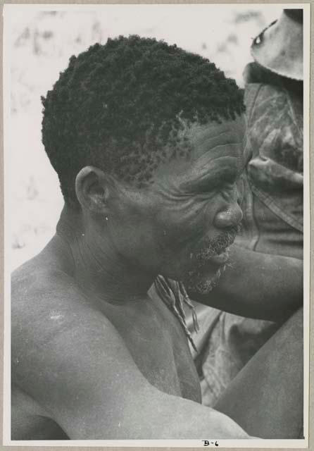 Portrait of a man sitting seen from the side, close-up (print is a cropped image)