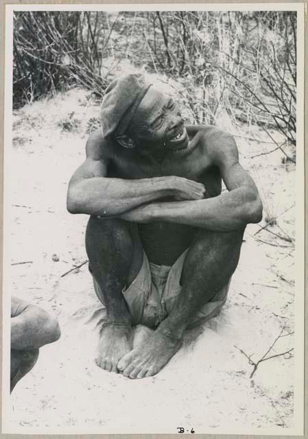 Portrait of a man wearing a hat, sitting with his arms crossed (print is a cropped image)