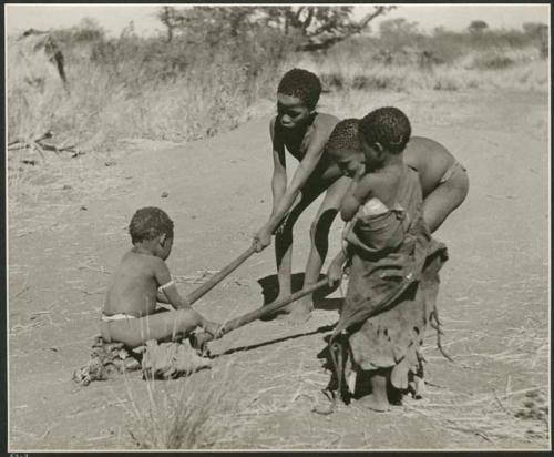 "Pulling on Kaross / Pulling on Gemsbok Horns / Carrying on Kaross "Airplane".": Tsamgao (≠Toma's son) and an unidentified boy pulling /Qui (son of Khuan//a) on gemsbok horns, with Be watching them (print is a cropped image)