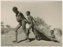 "Pulling on Kaross / Pulling on Gemsbok Horns / Carrying on Kaross "Airplane".": Two boys pulling "Little /Qui" on a kaross, a game they frequently played (print is a cropped image)