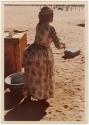 "Misc. prints with no numbers": Woman wearing a dress, standing next to a metal basin