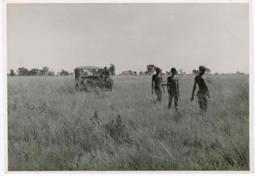 [No folder]: Three hunters walking, with the expedition jeep behind them