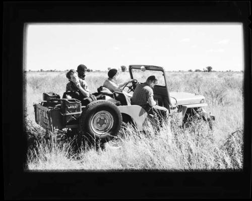 [No folder]: John Marshall driving a truck and Elizabeth Marshall Thomas eating something in the backseat, with two other people present