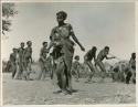 Woman dancing, with a group of people dancing behind her (print is a cropped image)