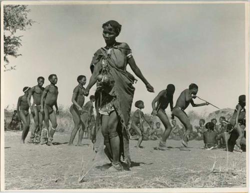 Woman dancing, with a group of people dancing behind her (print is a cropped image)