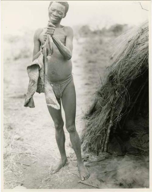 Gau (husband of Be and Khuan//a) standing next to a skerm, working on a skin to soften it