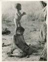 N!whakwe standing on his mother Tsekue's shoulder to look over the grass to see what was making noise (print is a cropped image)