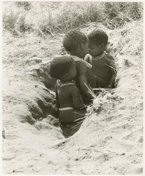 /Gaishay, Bau, and Debe playing in a hole in the ground (print is a cropped image)