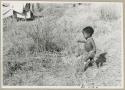 Ju/'hoan boy walking in grass (print is a cropped image)