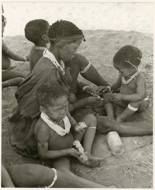 Di!ai giving food to her sons, /Gaishay and Debe (print is a cropped image)