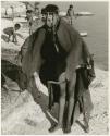 Woman bathing at Nama Pan, standing with her kaross over her shoulder; unidentified children in the background (print is a cropped image)