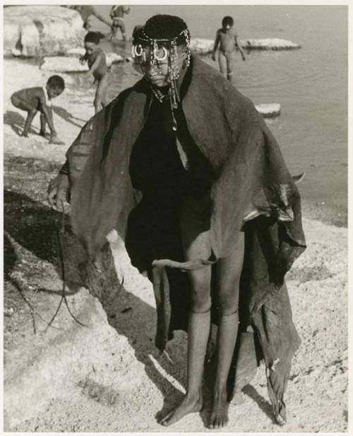 Woman bathing at Nama Pan, standing with her kaross over her shoulder; unidentified children in the background (print is a cropped image)