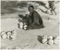 Khuan//a (Gau's wife) sitting with ostrich egg shells (print is a cropped image)