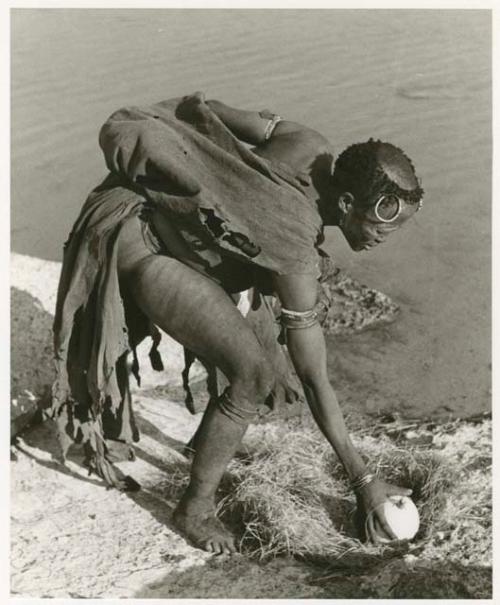 Khuan//a (Gau's wife) picking up an ostrich eggshell (print is a cropped image)