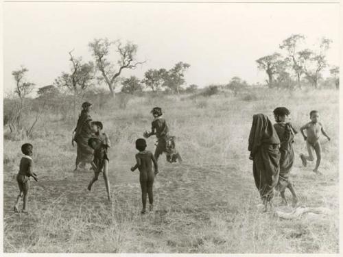 Girls playing N!owa t/ama (melon tossing game) / tamah n!o’an (ball game); other children present in the background (print is a cropped image)
