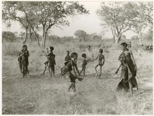 Girls playing N!owa t/ama (melon tossing game) / tamah n!o’an (ball game); other children present in the background (print is a cropped image)
