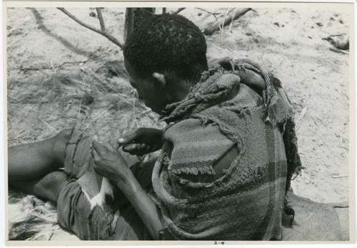 [No folder title]: Tama sewing, showing how he makes a hole with an awl for the thread to go through, close-up (from color slide 2001.29.8361)