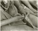 Woman's hands sewing beads onto a leather strip, close-up (print is a cropped image)