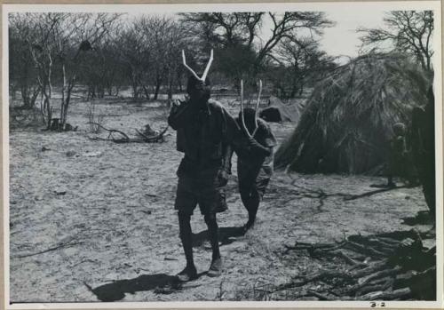 [No folder title]: Two men performing the Eland Dance, holding wooden horns up to their heads
