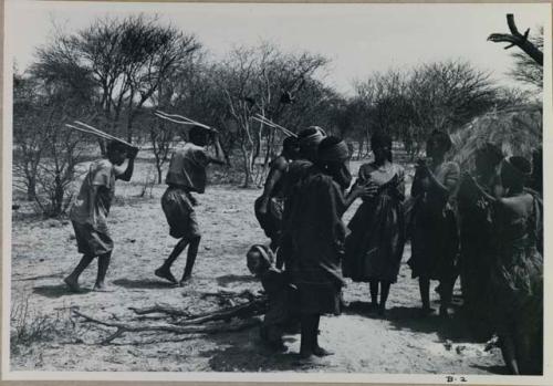 [No folder title]: Group of people performing the Eland Dance; group of women clapping; men holding wooden horns to their heads