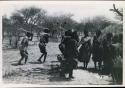 [No folder title]: Group of people performing the Eland Dance; group of women clapping; men holding wooden horns to their heads