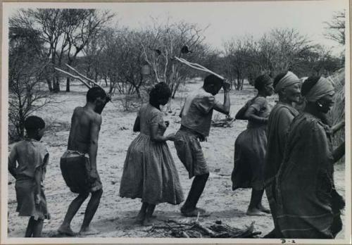 [No folder title]: Group of people performing the Eland Dance; a line of people, men holding wooden horns to their heads