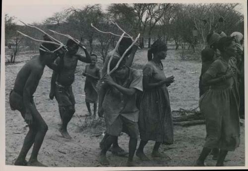 [No folder title]: Group of people performing the Eland Dance; group of women clapping; men with wooden horns on their heads

