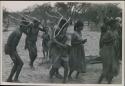 [No folder title]: Group of people performing the Eland Dance; group of women clapping; men with wooden horns on their heads

