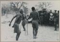 Group of men dancing, people standing on the side