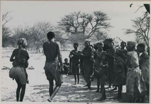 N/kxabe and Tama, seen from behind, next to a group of women clapping