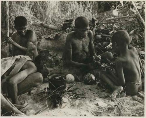 [No folder title]: //Kuǂtera, DaSi!Na, and /Twikwe sitting around a fire cooking in a pot; /Twikwe giving food to !Ou/ke


