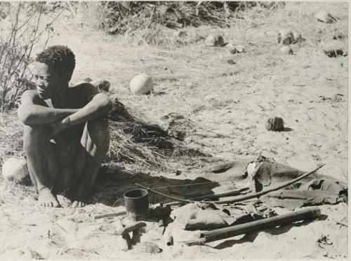 [No folder title]: Oukwane sitting, with his possessions on the ground next to him





