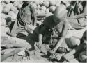 [No folder title]: Girl pounding tsama melon seeds in a piece of gourd used as a receptacle
