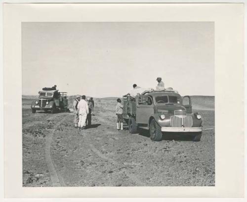 "1950's 400 series": Expedition members standing on and next to trucks (print is a cropped image)