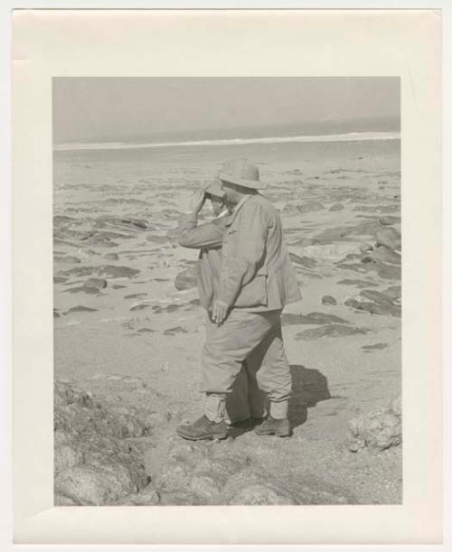 "1950's 400 series": Two expedition members standing on beach looking at water (print is a cropped image)