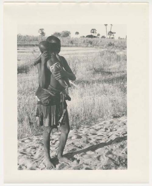 "Glossy duplicates of / 1950 Merl La Voy prints / 400 series": Woman standing and holding a baby (print is a cropped image)