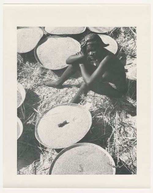 "1950 '400 Series' / 87 B/W prints (some duplicates) / Ovamboland": Woman sitting next to baskets of grain (print is a cropped image)