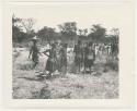 "1950 '400 Series' / 87 B/W prints (some duplicates) / Ovamboland": Group of people standing, with baskets of grain on the ground near them (print is a cropped image)