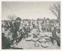 "1950 '400 Series' / 87 B/W prints (some duplicates) / Ovamboland": Group of people standing and sitting, with baskets of grain on the ground near them (print is a cropped image)