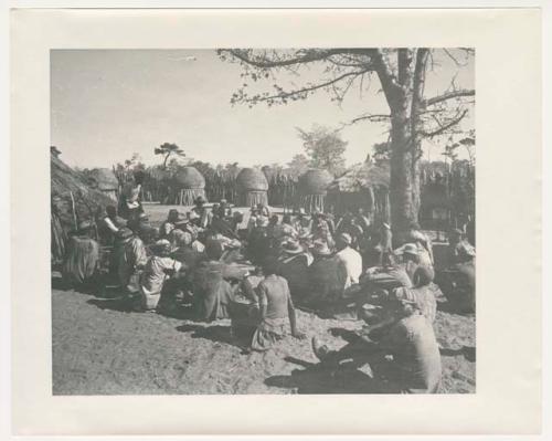 "1950 '400 Series' / 87 B/W prints (some duplicates) / Ovamboland": Group of people sitting, with storage baskets in background (print is a cropped image)