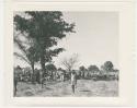 "1950 '400 Series' / 87 B/W prints (some duplicates) / Ovamboland": People walking in front of a large group of people sitting (print is a cropped image)