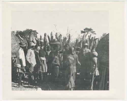 "1950 '400 Series' / 87 B/W prints (some duplicates) / Ovamboland": Group of people sitting and standing, with baskets of grain on the ground near them (print is a cropped image)