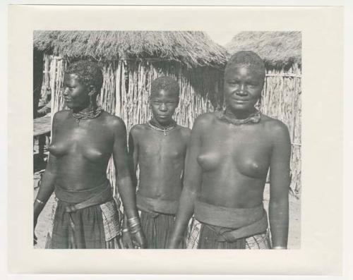 "1950 '400 Series' / 87 B/W prints (some duplicates) / Ovamboland": Woman and girls standing in front of huts (print is a cropped image)